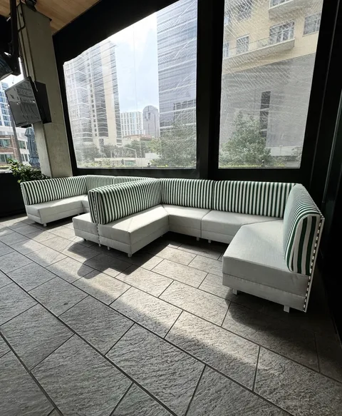 Green-and-white striped corner lounge seating with light cushions at The Henry in Dallas