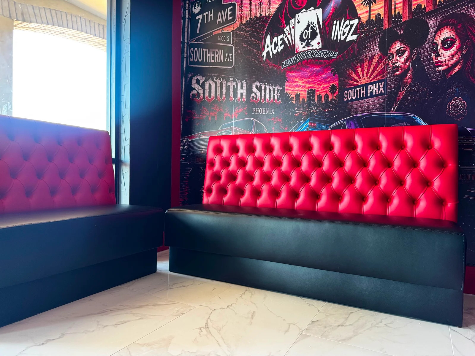 Red diamond-tufted booth backs and black seats beneath the Ace of Wingz mural in Phoenix