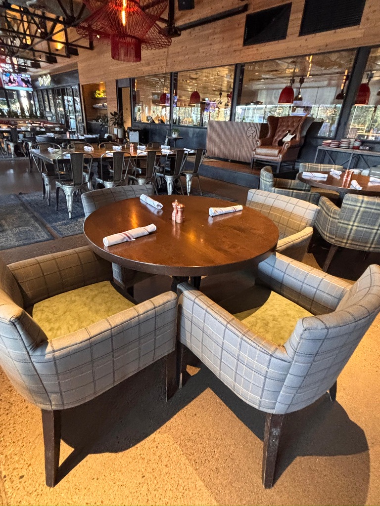 Plaid upholstered dining chairs with green seats at Culinary Dropout in downtown Gilbert, with workshop views included in the gallery
