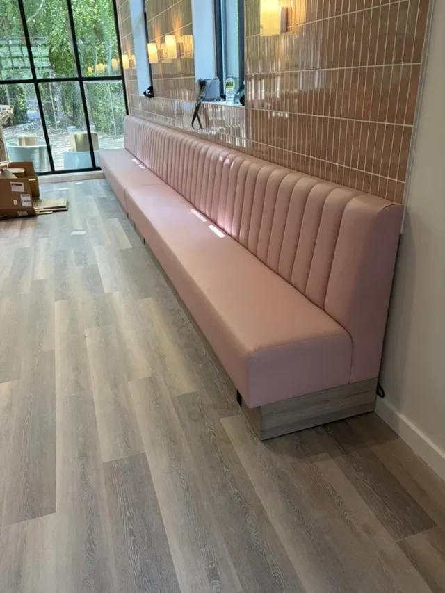 Pink channel banquette fitted along a tiled wall