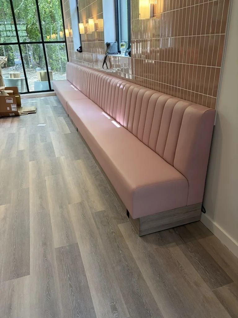 Pink channel banquette fitted along a tiled wall