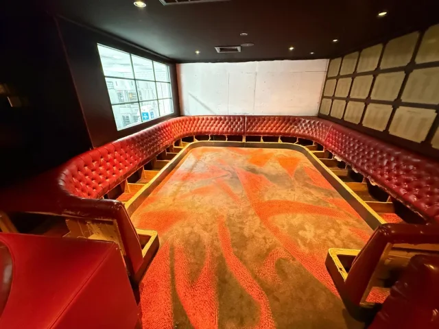 Red tufted seating with cushions removed and seat framing exposed