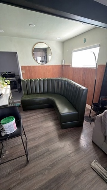 Dark upholstered corner banquette with vertical-channel backs inside a residential room