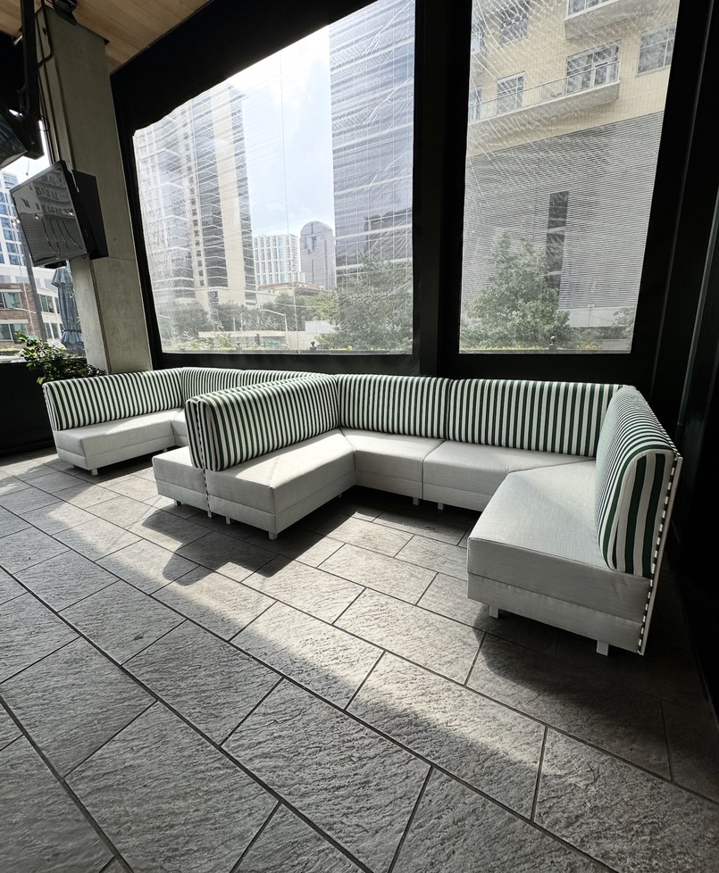 Green-and-white striped corner lounge seating with light cushions at The Henry in Dallas, Texas