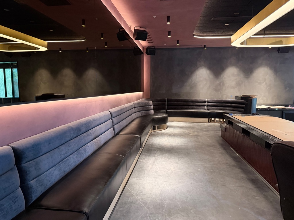 Straight and curved banquettes with horizontal-channel backs and dark seats during installation at The Rosewelt in downtown Phoenix
