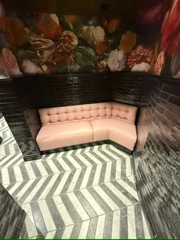 A pale pink tufted corner booth photographed in a restaurant interior