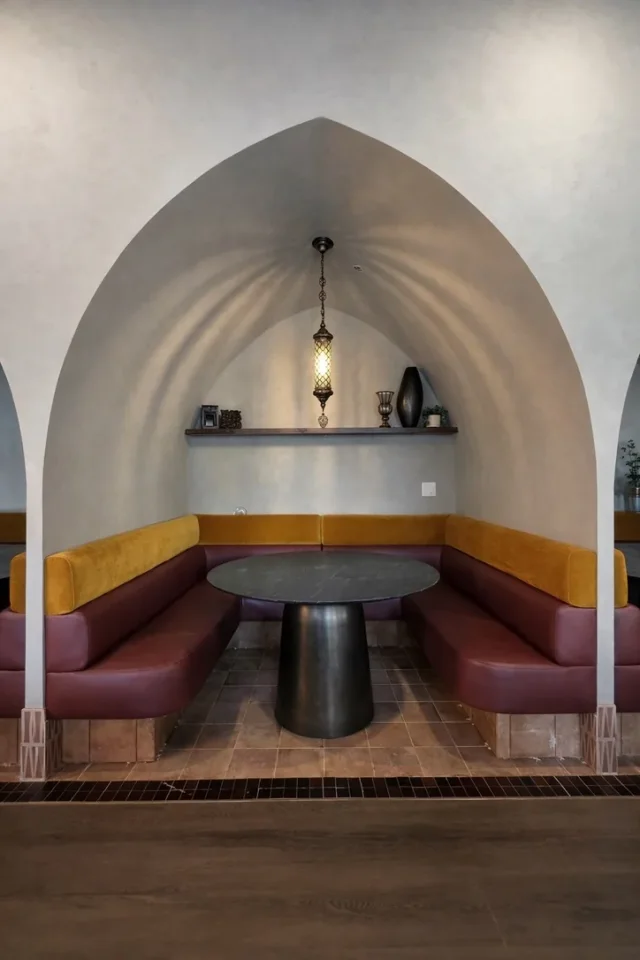 Mustard and burgundy booth fitted beneath a restaurant arch